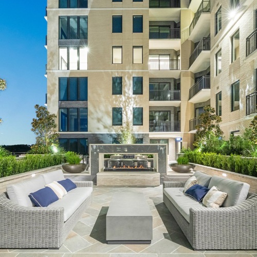 an outdoor firepit with lounge seating and lush landscaping
